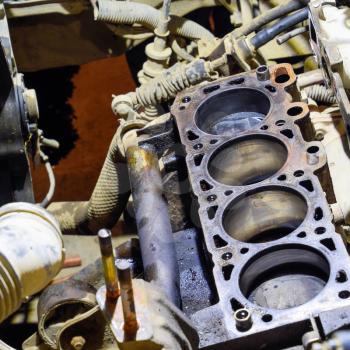 The cylinder block of the four-cylinder engine. Disassembled motor vehicle for repair. Parts in engine oil. Car engine repair in the service.