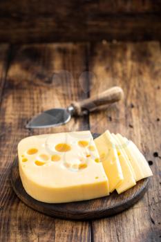 Delicious Swiss yellow cheese on dark wooden rustic background closeup