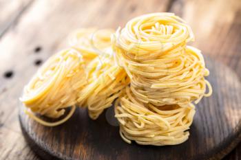 Raw all'uovo pasta, egg noodles on dark wooden rustic background, traditional italian cuisine