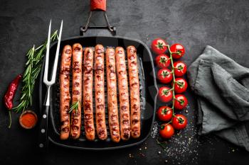 Grilled sausages bratwurst in grill frying-pan on black background. Top view. Traditional German cuisine. Stock image