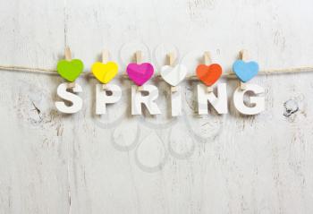 word spring with white letters with colored hearts clothespins on a white background old