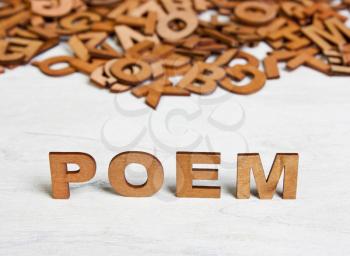 Word Poem made with wooden letters on a background of other blurred letters