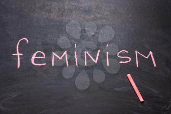 The word feminism is written chalk on the blackboard. The concept of equality