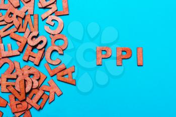 abbreviation PPI - Payment Protection Insurance.Wooden letters on blue background