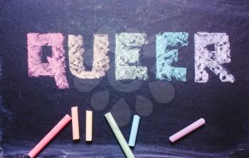  word Queer on a chalkboard, a symbol of LGBT, the colors of the rainbow