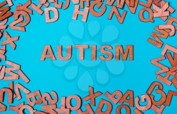 The word Autism from wooden letters on a blue background. The problem is in socialization, communication