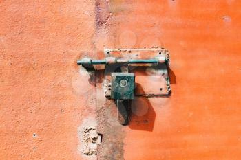 Old, iron, orange rusty metal door with lock and shutter