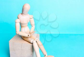 Wooden human figure on a blue background. The concept of pain in the abdomen, stomach, menstruation