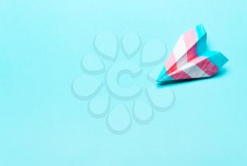 Paper airplane in transgender flag on a blue background