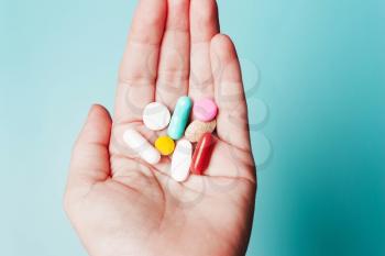 Pills in hand on a blue background. The concept of health, treatment, disease