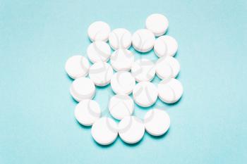 Round, white pills on a blue background. Disease treatment concept, healthcare