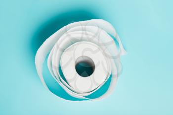 Soft single roll of white toilet paper on a blue background.  The concept of hygiene, cleanliness