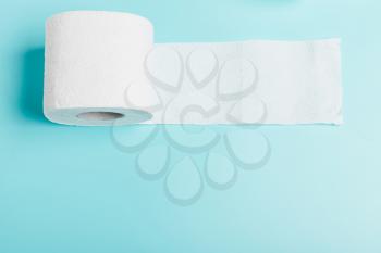 Roll of white toilet white paper on a blue background. Top view. The concept of hygiene, cleanliness