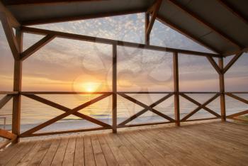 Arbour on the sea shore on the beach at sunset. Nature and indoor composition.