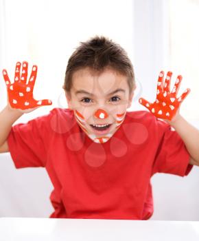 Portrait of a cute boy showing her hands painted in bright colors