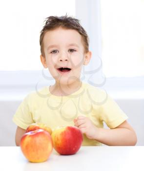 Portrait of a happy little boy with red apples