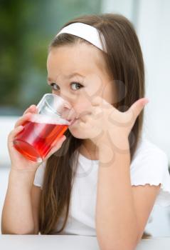Little girl is drinking cherry juice showing thumb up gesture