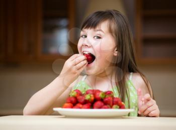 Happy little girl eats strawberries