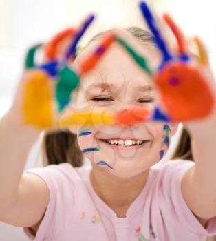 Portrait of a cute cheerful girl showing her hands painted in bright colors