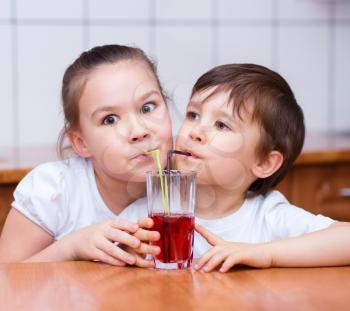 Cute little girl and boy drink juice