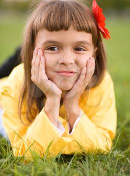Little girl is daydreaming lying on green grass