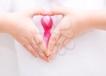 healthcare and medicine concept - womans hands holding pink breast cancer awareness ribbon