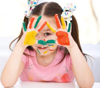 Portrait of a cute cheerful girl showing her hands painted in bright colors