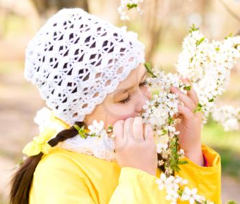 Portrait of a cute little girl smelling flowers outdoors