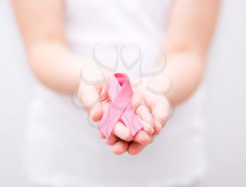 healthcare and medicine concept - girl hands holding pink breast cancer awareness ribbon