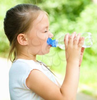 Cute little girl drinks water from a plastic bottle