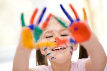 Portrait of a cute cheerful girl showing her hands painted in bright colors