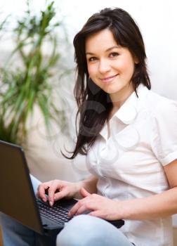 Young woman is playing on laptop, indoor shoot