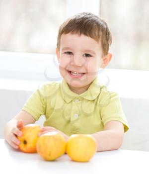 Portrait of a happy little boy with yellow apples
