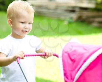 Little cute girl playing with a pram for dolls