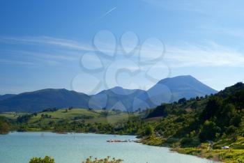 The idyllic countryside of Italy. The glassy surface of the lake and the blue mountains.