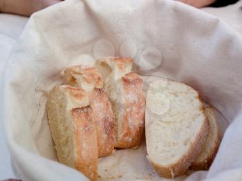 Slices of bread with Golden crust in white basket. Freshly baked and fragrant bread on table in restaurant. Italy.