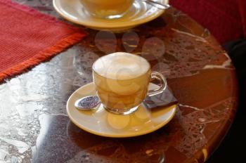 White porcelain Cup with gourmet coffee on marble table in Italian bar. A feast for the sweet tooth.