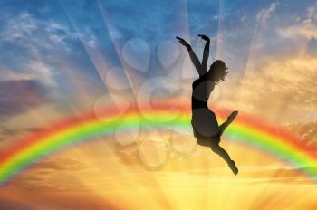Rainbow and happiness. Happy woman jumping at sunset near the rainbow