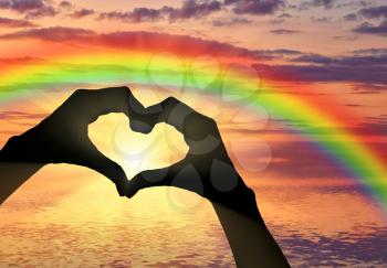 Love. Hand gesture in the form of heart on the background of rainbow sea sunset