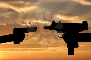 Terrorism and conflict. Weapons in the hands of people at sunset background