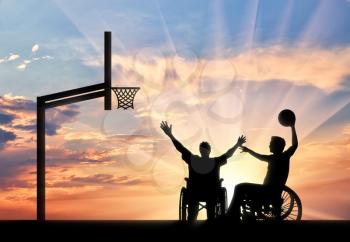 Disabled sportsman in wheelchair play basketball on basketball court with ball sunset. Concept sport and willpower