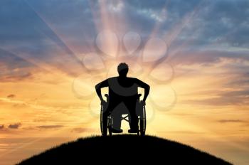 Disabled concept. Silhouette of disabled person in a wheelchair chair at sunset