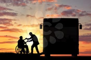 Disabled person in wheelchair to help go to bus on sunset. Concept help disabled