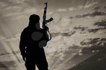 Silhouette of  terrorist with a weapon against a background of a sunset 