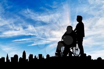 Concept of disability and old age. Silhouette of a man looking after a disabled person on a background of cityscape