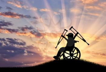 Happy boy in wheelchair with crutches sunset. Concept happy disabled
