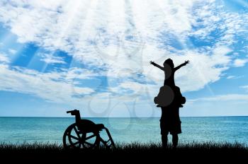 Happy disabled child on shoulders of dad and wheelchair near sea day. Concept happy child disabled