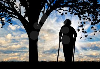 Silhouette of an old woman on crutches resting under a tree. Concept of disability and old age