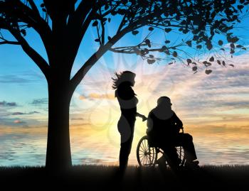 Silhouette of nurse caring for a disabled person in a wheelchair resting under a tree near sea. Concept of caring for a disabled person and house of aged