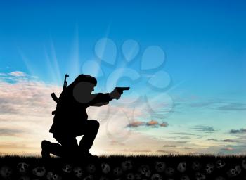 Concept of terrorism. Silhouette of a terrorist with a gun on the ground of turtles at sunset